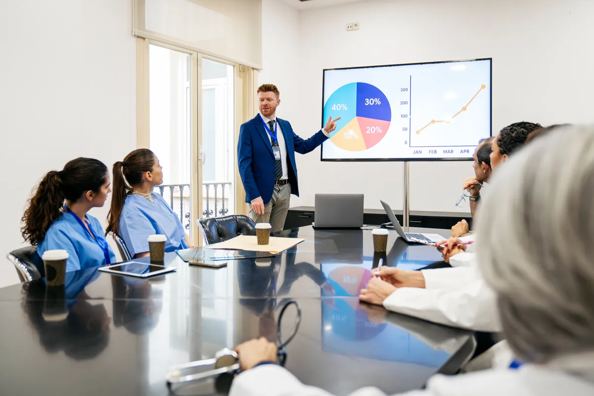 A presenter takes a clinic team through a chart in a meeting room