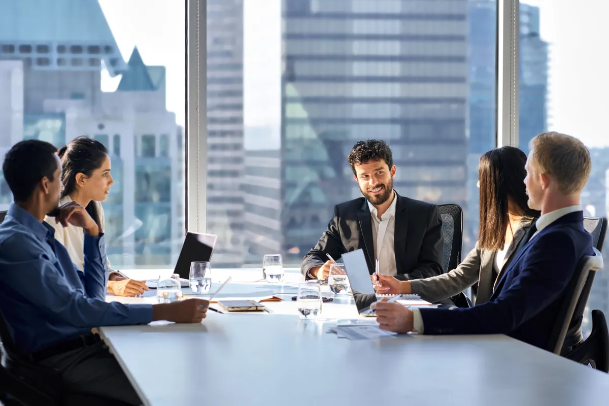 A leadership team meets around a boardroom table in a high-rise office